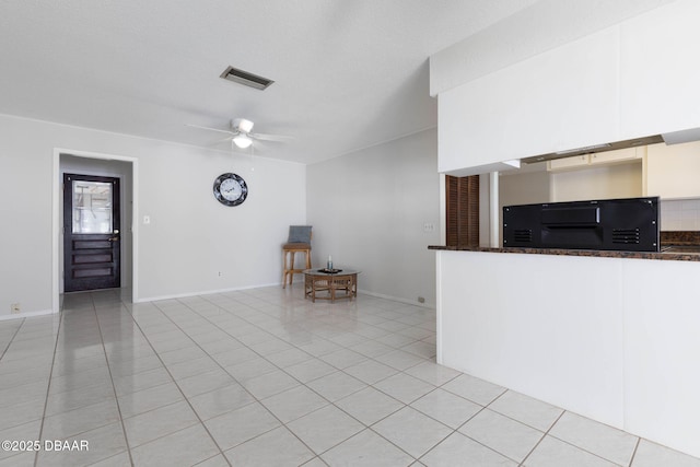 unfurnished living room featuring ceiling fan, light tile patterned floors, and a textured ceiling