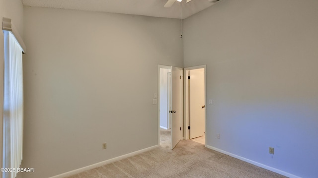 carpeted empty room featuring ceiling fan and a high ceiling