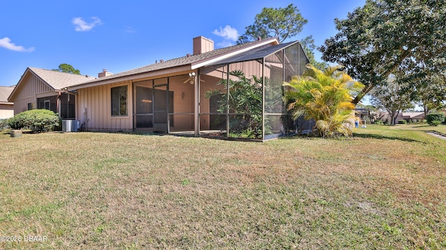 rear view of property featuring cooling unit and a lawn