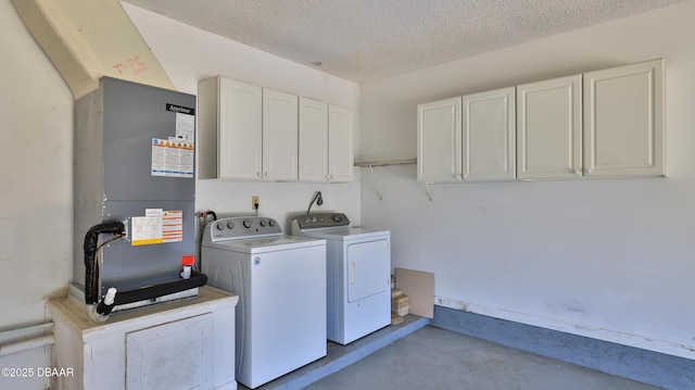 laundry room featuring heating unit, a textured ceiling, cabinets, and washing machine and clothes dryer