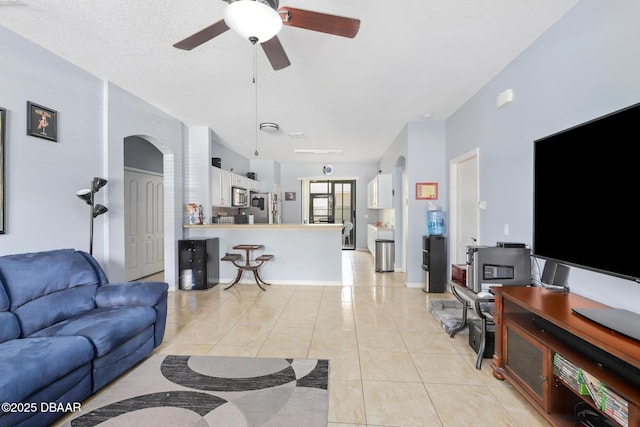 living room featuring ceiling fan, light tile patterned floors, and a textured ceiling