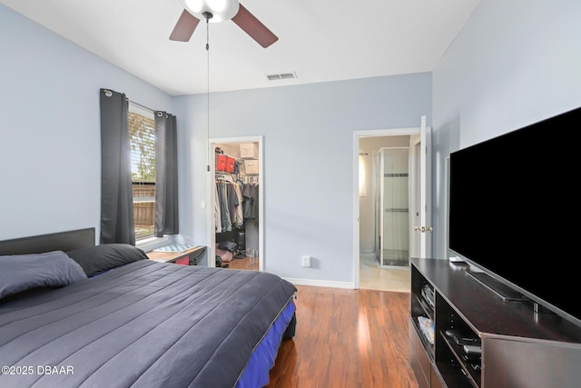 bedroom featuring a closet, a walk in closet, ceiling fan, and dark hardwood / wood-style flooring