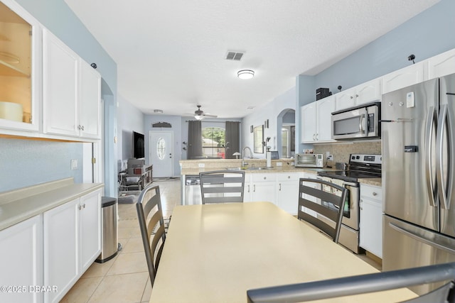 kitchen featuring ceiling fan, white cabinets, a textured ceiling, light tile patterned floors, and appliances with stainless steel finishes