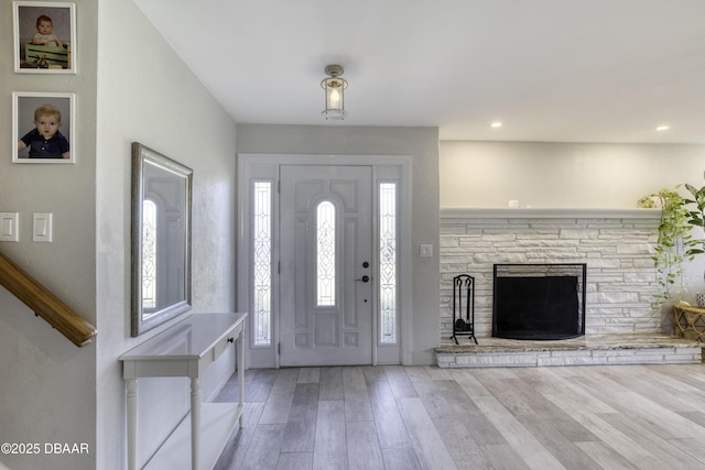 entrance foyer featuring a stone fireplace, recessed lighting, and wood finished floors