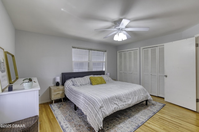 bedroom with ceiling fan, baseboards, multiple closets, and light wood-type flooring