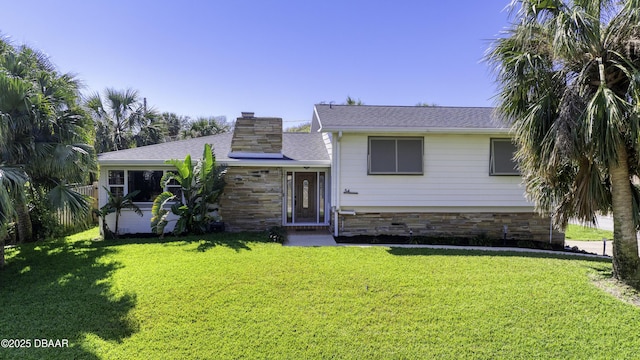 tri-level home with stone siding, a front lawn, roof with shingles, and a chimney