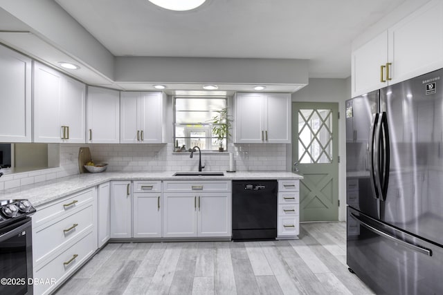 kitchen with a wealth of natural light, decorative backsplash, black appliances, and a sink