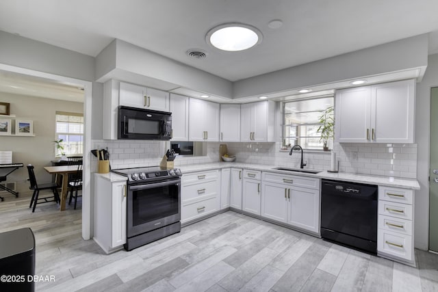 kitchen featuring decorative backsplash, plenty of natural light, black appliances, and a sink