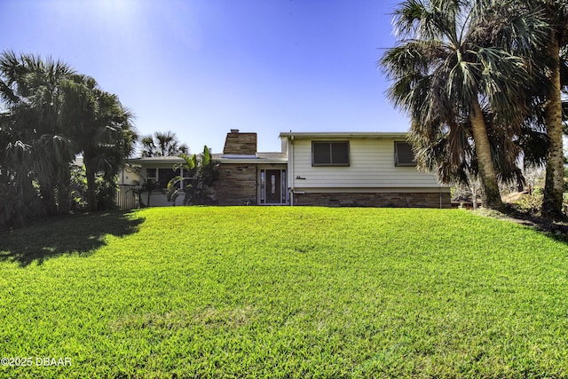 rear view of property featuring a lawn and a chimney