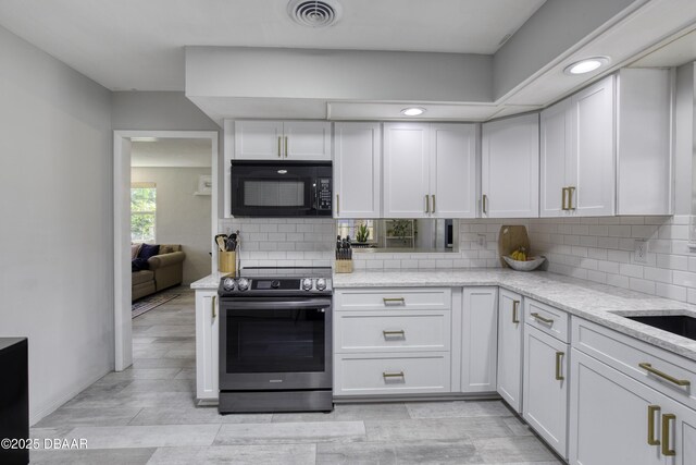 kitchen featuring visible vents, black microwave, light stone countertops, electric stove, and white cabinetry