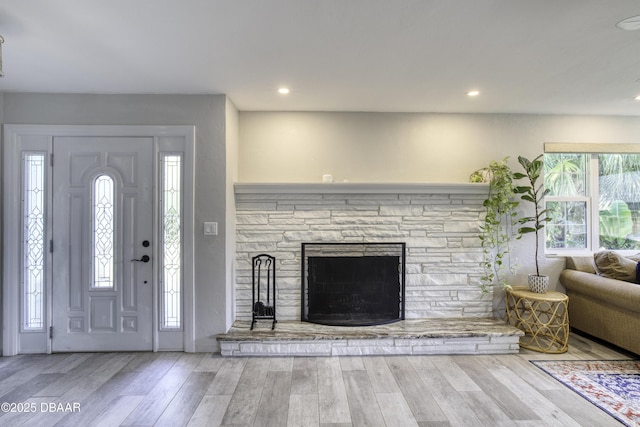 foyer entrance featuring a stone fireplace, recessed lighting, and wood finished floors