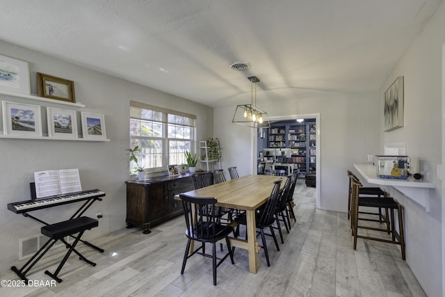 dining area featuring a chandelier, visible vents, and light wood-style flooring