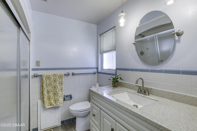 full bathroom featuring toilet, a stall shower, tile walls, wainscoting, and vanity