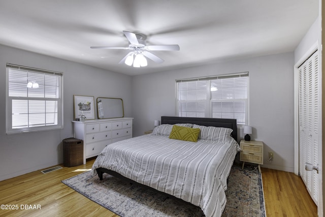 bedroom featuring a closet, baseboards, visible vents, and light wood finished floors