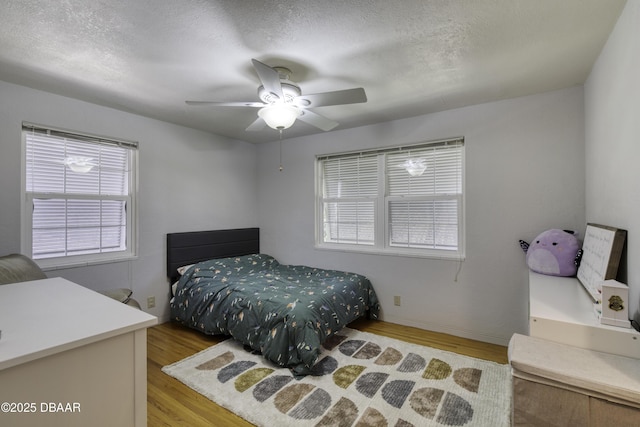 bedroom with a textured ceiling, ceiling fan, and wood finished floors