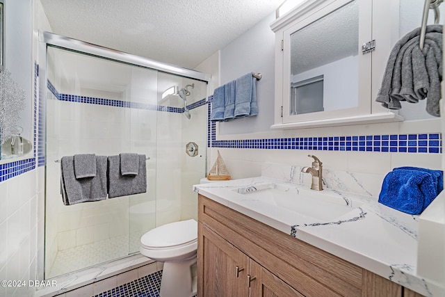 bathroom with tile walls, an enclosed shower, vanity, and a textured ceiling