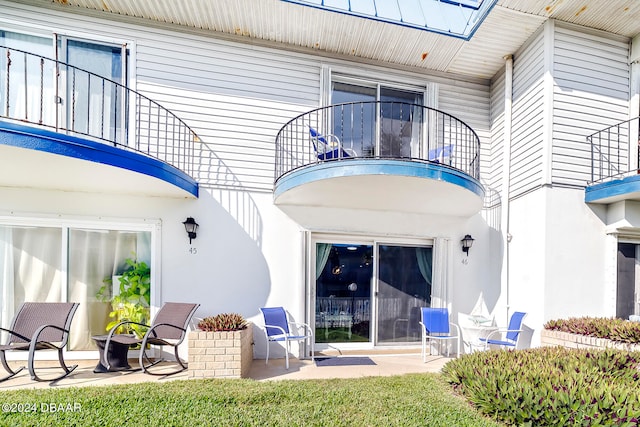 back of house featuring a balcony, a yard, and a patio