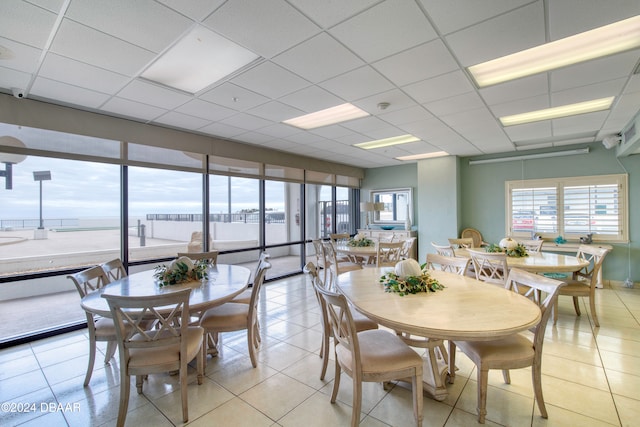 tiled dining area with a water view and a drop ceiling