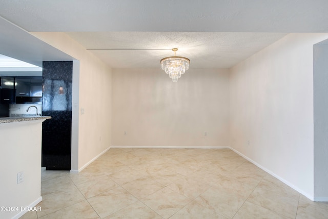 unfurnished dining area with a chandelier and a textured ceiling