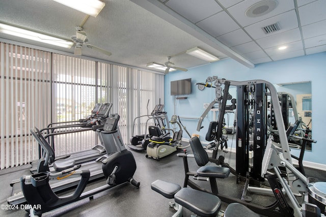 exercise room with ceiling fan and a drop ceiling