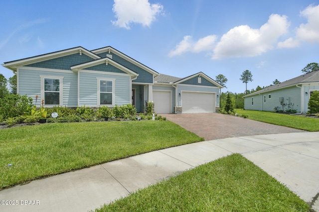 83 Reverie Dr N, Palm Coast, FL 32137 - view of front facade featuring decorative driveway, an attached garage, a front lawn, and stone siding