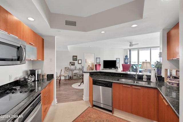 kitchen featuring dark stone counters, appliances with stainless steel finishes, sink, and light hardwood / wood-style floors