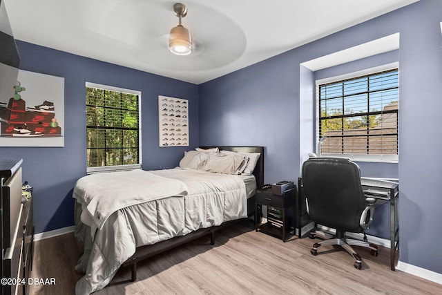 bedroom featuring ceiling fan, multiple windows, and light wood-type flooring