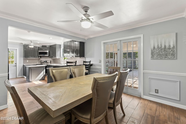 dining room featuring light wood-type flooring, a wealth of natural light, ceiling fan, and crown molding