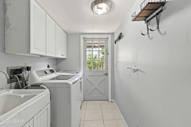 clothes washing area with cabinets, light tile patterned flooring, sink, independent washer and dryer, and a barn door