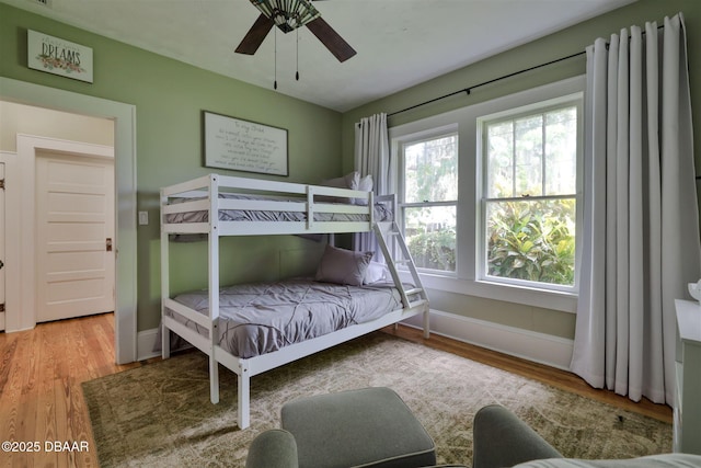 bedroom with a ceiling fan, wood finished floors, and baseboards