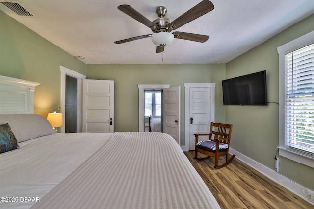 bedroom with visible vents, baseboards, wood finished floors, and a ceiling fan