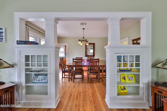 kitchen with decorative light fixtures, wood finished floors, visible vents, and ornate columns