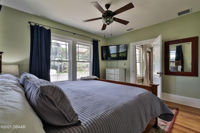 bedroom with visible vents, baseboards, wood finished floors, and a ceiling fan