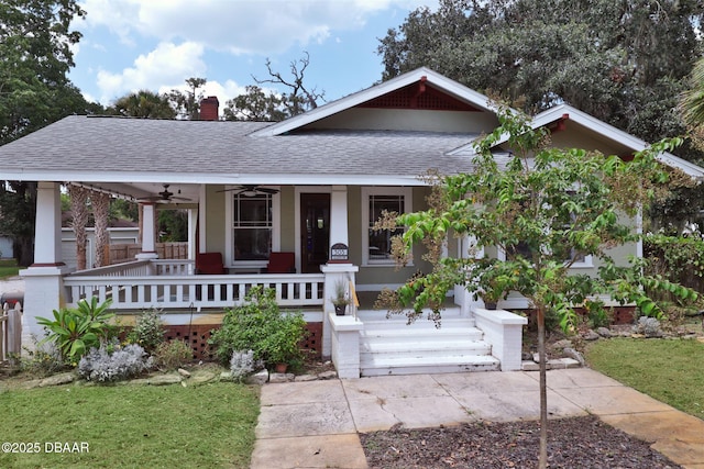 view of front of house with a ceiling fan, covered porch, a chimney, and a shingled roof