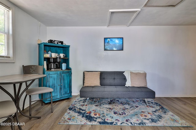 living area with attic access, wood finished floors, and baseboards