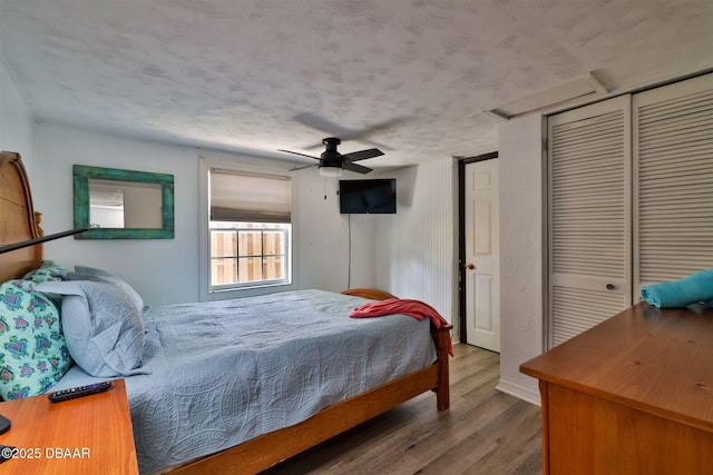 bedroom featuring a ceiling fan, wood finished floors, and a textured ceiling