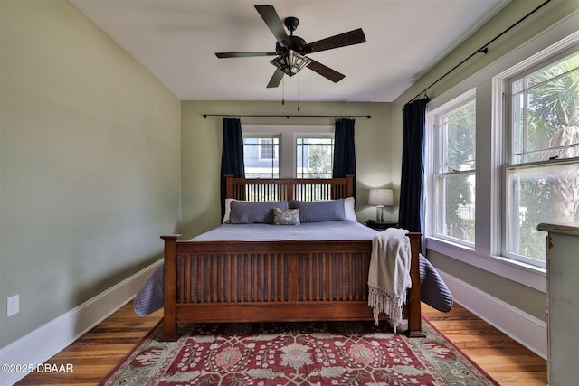 bedroom featuring a ceiling fan, baseboards, and wood finished floors