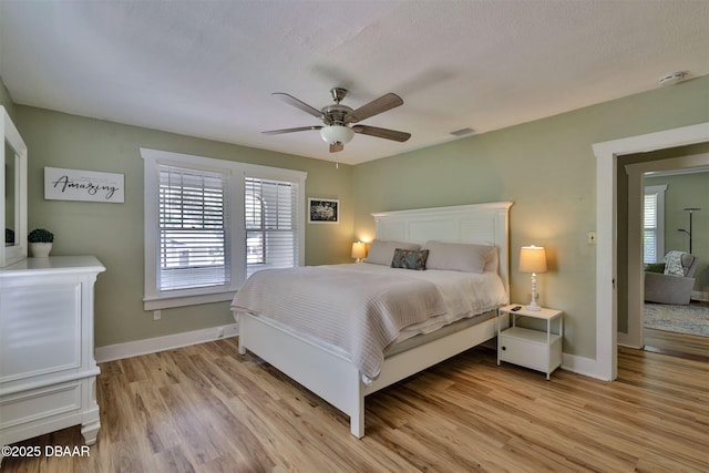 bedroom with visible vents, light wood-style flooring, baseboards, and ceiling fan