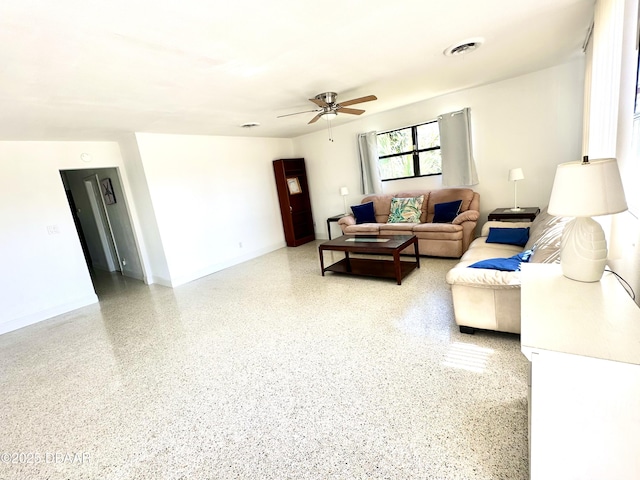 living area featuring visible vents, ceiling fan, light speckled floor, and baseboards