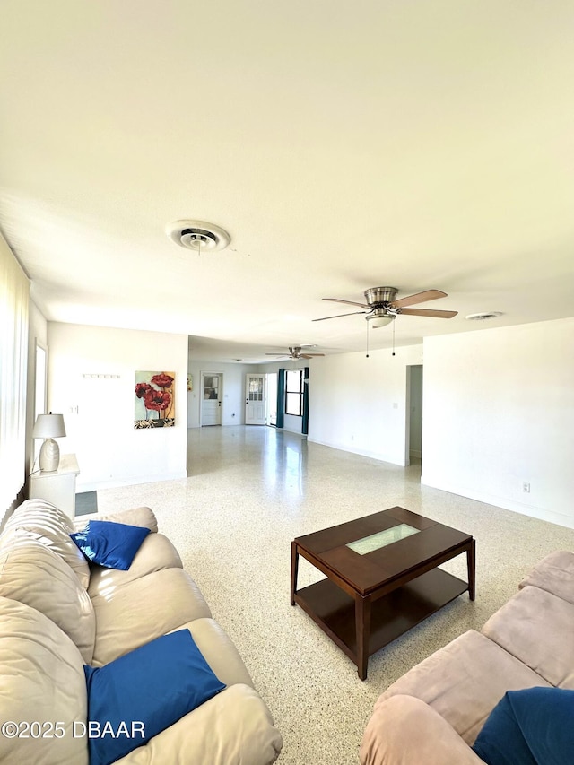 living room with speckled floor, a ceiling fan, and visible vents