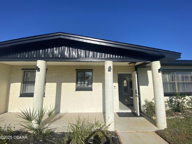 view of exterior entry with concrete block siding and a porch