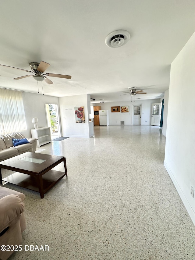 living room with visible vents, ceiling fan, speckled floor, and baseboards