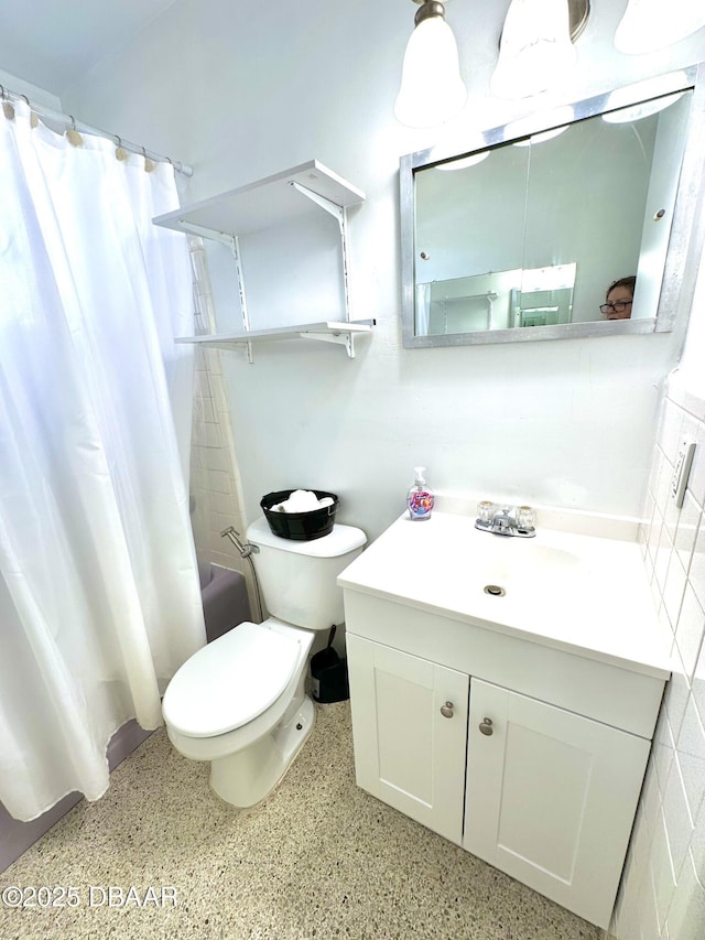 full bathroom with speckled floor, toilet, shower / tub combo with curtain, and vanity