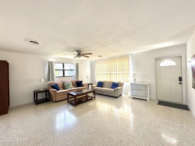 living room featuring speckled floor, ceiling fan, baseboards, and visible vents