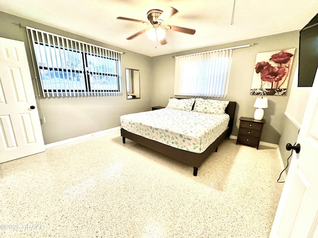 bedroom with ceiling fan, baseboards, and multiple windows