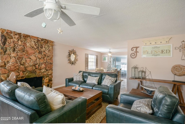 living room featuring a ceiling fan, a fireplace, and a textured ceiling