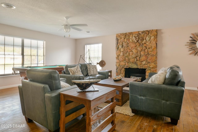 living room with a stone fireplace, pool table, wood finished floors, a ceiling fan, and baseboards