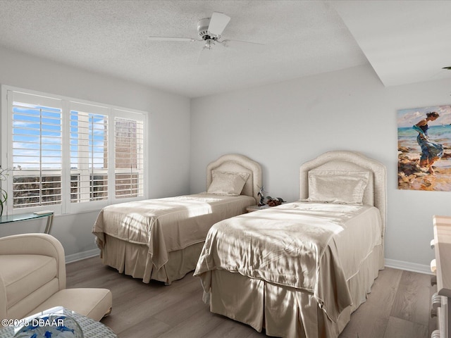 bedroom featuring a textured ceiling, baseboards, a ceiling fan, and wood finished floors