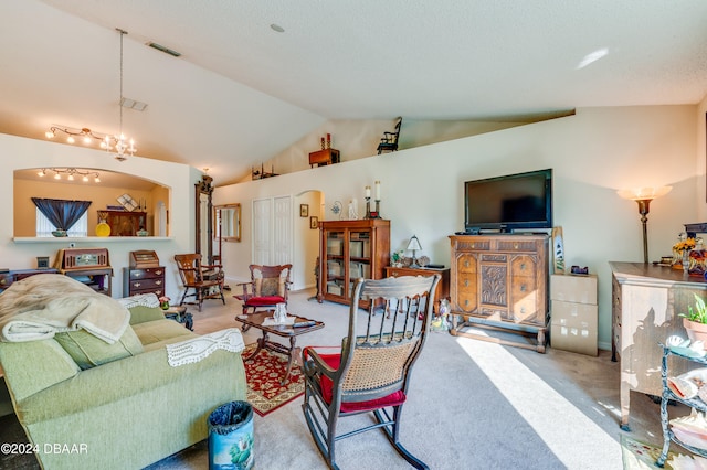 carpeted living room with a chandelier and vaulted ceiling