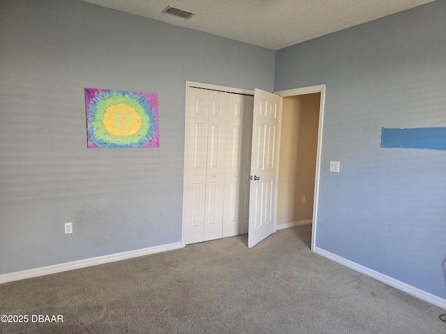 unfurnished bedroom with carpet, baseboards, visible vents, a closet, and a textured ceiling